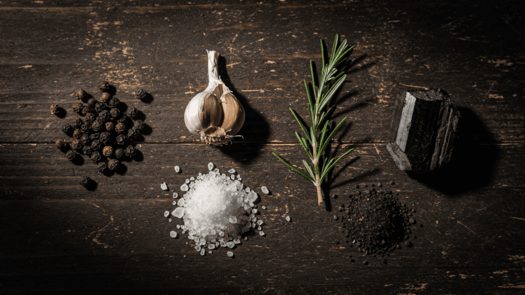 Protection amulet materials including black peppercorns, dried garlic, rosemary, sea salt, black salt, and black tourmaline