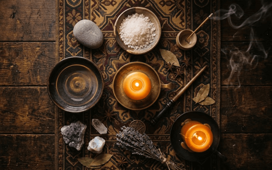 An overhead elemental altar with a stone and salt for earth, incense for air, candles for fire, and a bowl for water